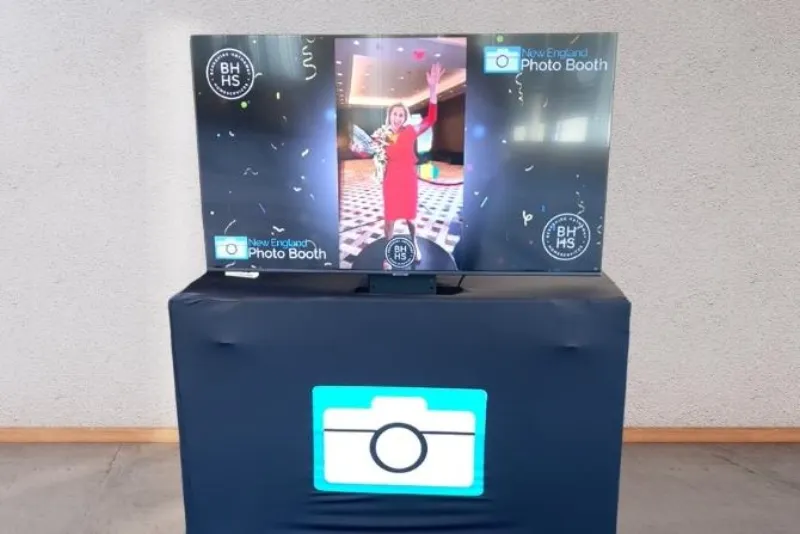 Professional 50-inch TV display showing live photo booth slideshow at an event