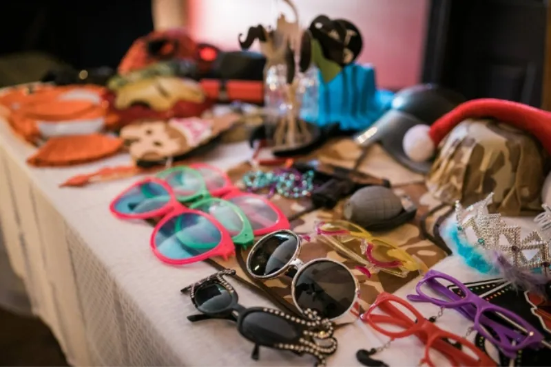 Wearable photo booth props including hats glasses and masks displayed on a table