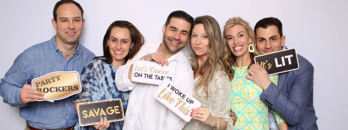 Photo booth prop signs spread across a table at an event