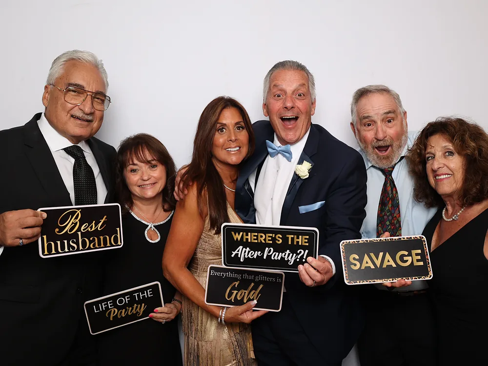 Multigenerational family in formal dress holding prop signs against a dark backdrop