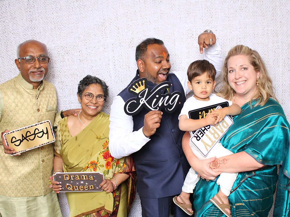 Family with a toddler holding King and Drama Queen prop signs against a light backdrop