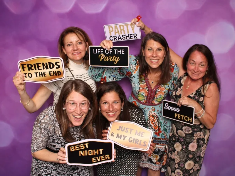 Corporate event guests with prop signs against a purple sparkle backdrop