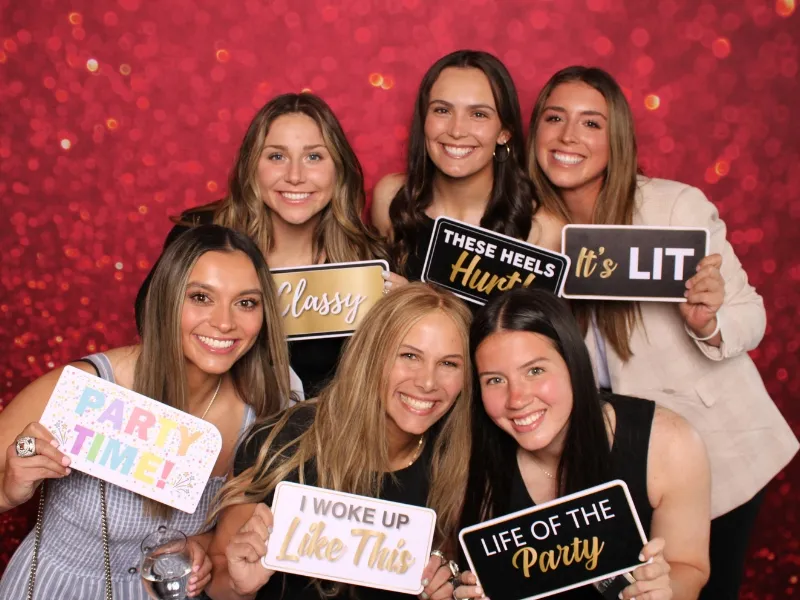 Young corporate women having fun with prop signs against a red backdrop