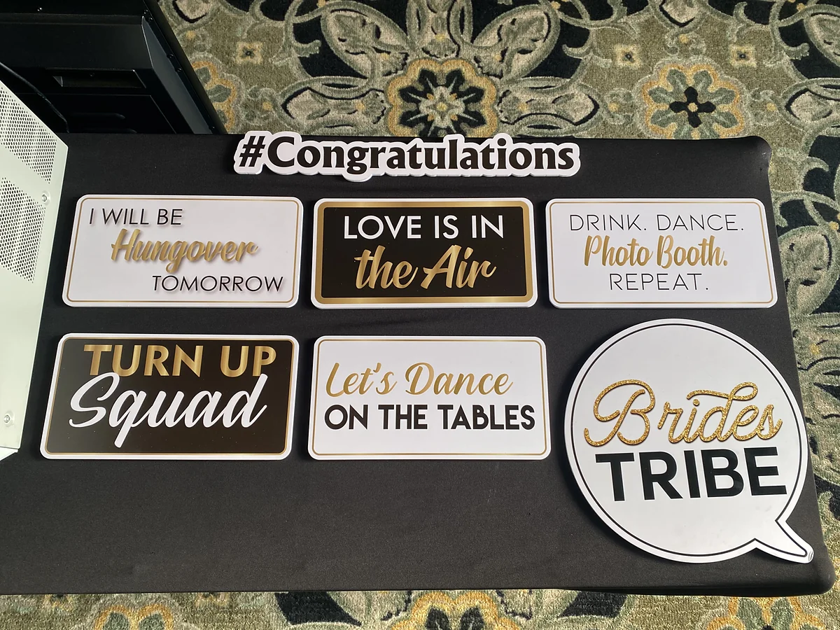 Wedding photo booth prop signs reading Brides Tribe, Love is in the Air, Congratulations and Let's Dance on the Tables