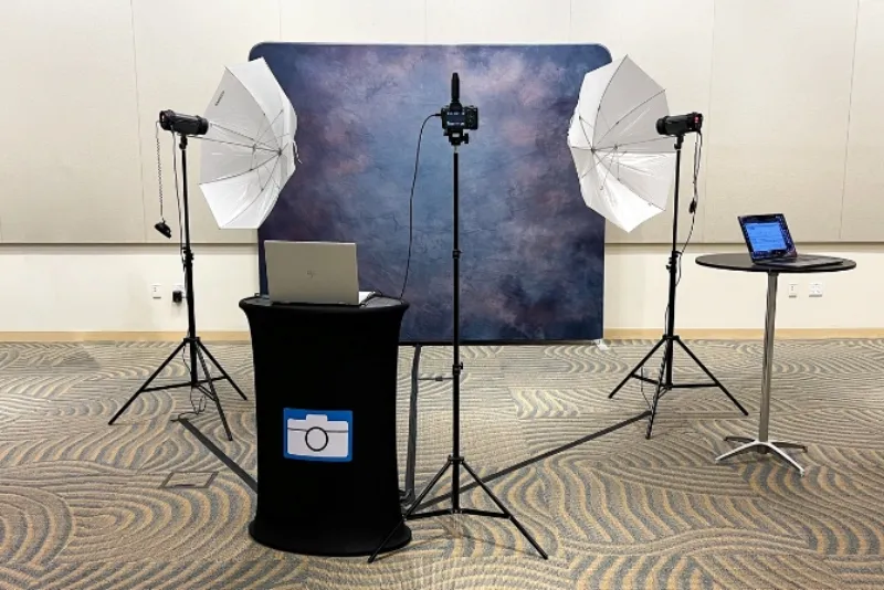 Professional headshot setup with tripod camera backdrop strobe flash heads and laptops