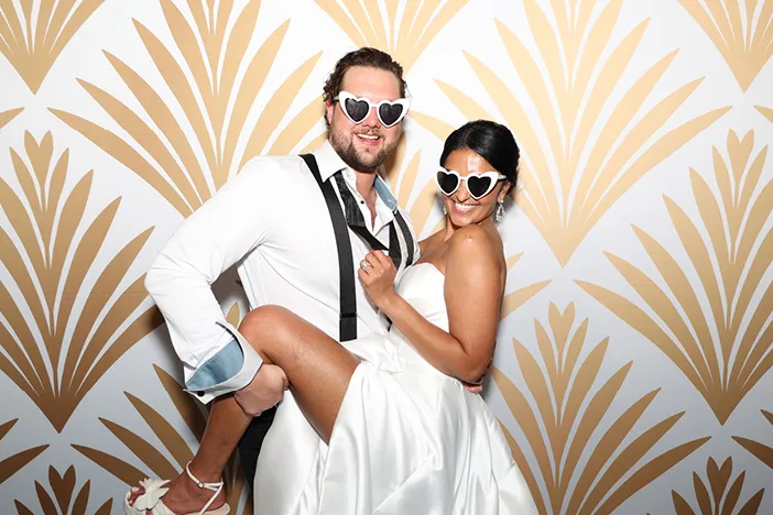 male coworkers at a business party in front of a silver photo booth back ground