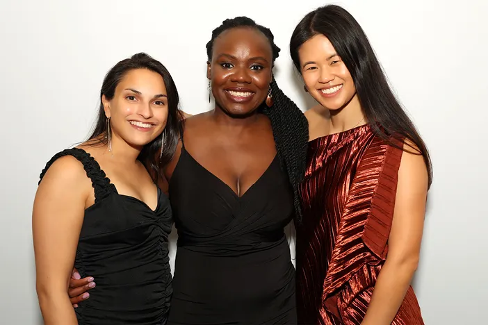 Three students pose infront of a green screen photo booth at a school event