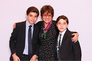 Two young boys pose with their grandma at a Mitzvah photo booth