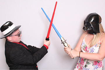 Siblings pretend fight with lightsabers in the photo booth at a mitzvah