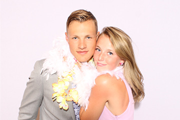Young school couple smiles simply together at the prom photo booth