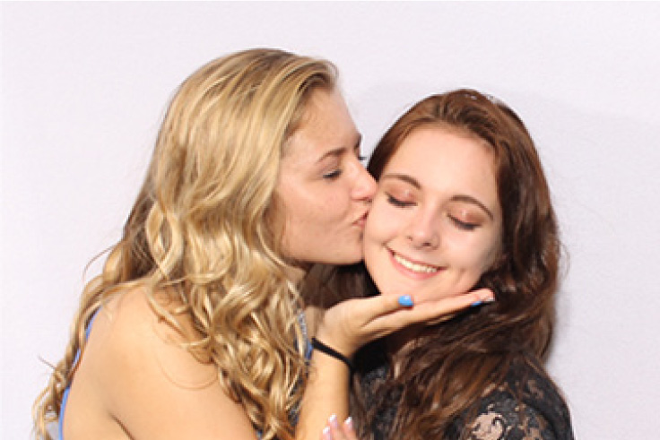 Girl friends share love at their school photo booth event in front of a white background