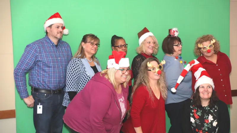 Group posing in front of a custom green screen background in a photo booth