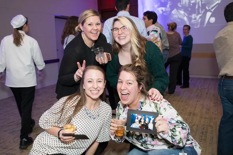 Roaming photographer photos alongside printed photo booth strips at corporate holiday party