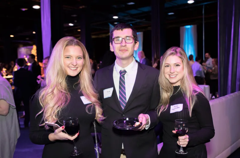 Guests posing for roaming photographer at a gala